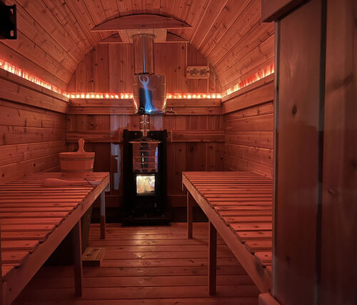 Inside the Flowing Flame sauna — wood stove, cedar benches, and warm glow